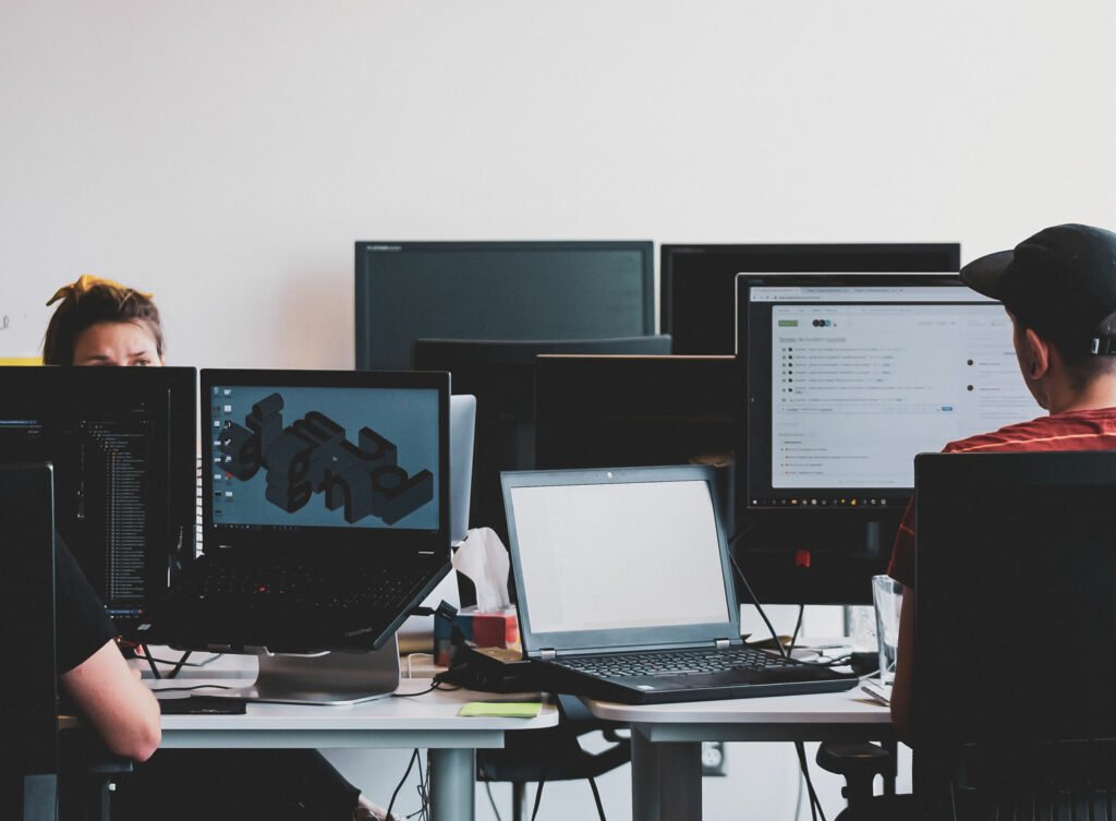 people working in an office with multiple screens