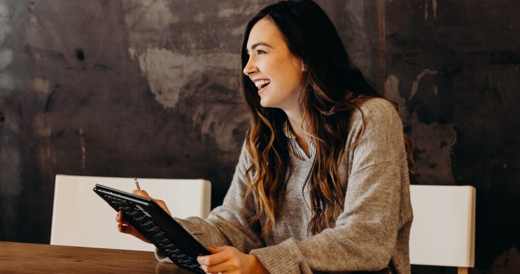 a woman holding a tablet and smiling