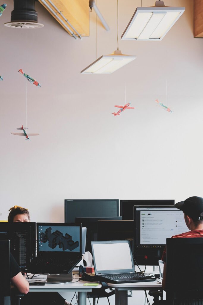 People working on laptops, paper airplanes suspended from the ceiling