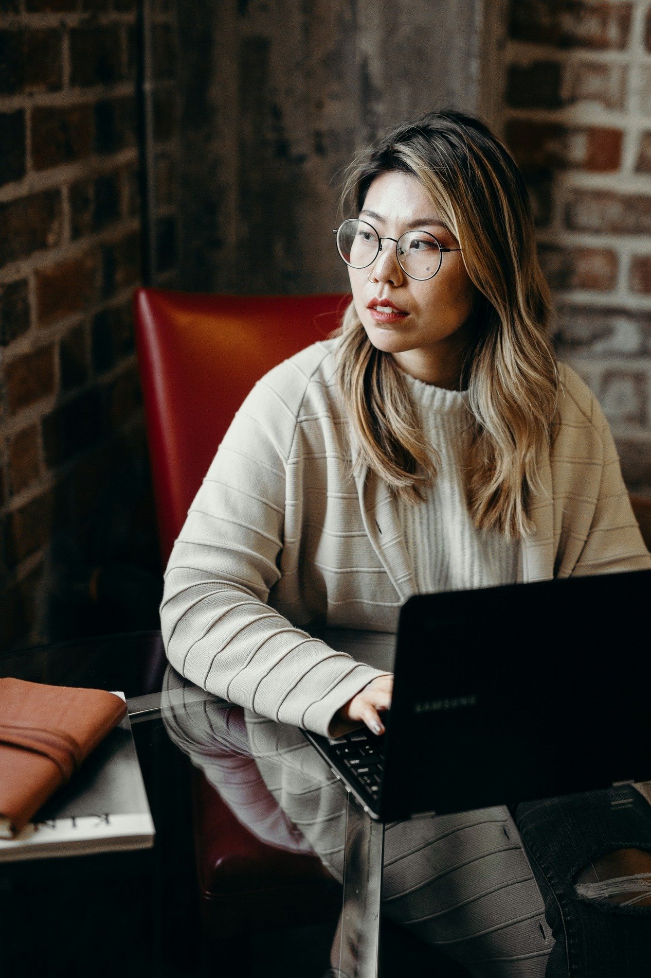 A woman sat on a chair with a laptop on her lap