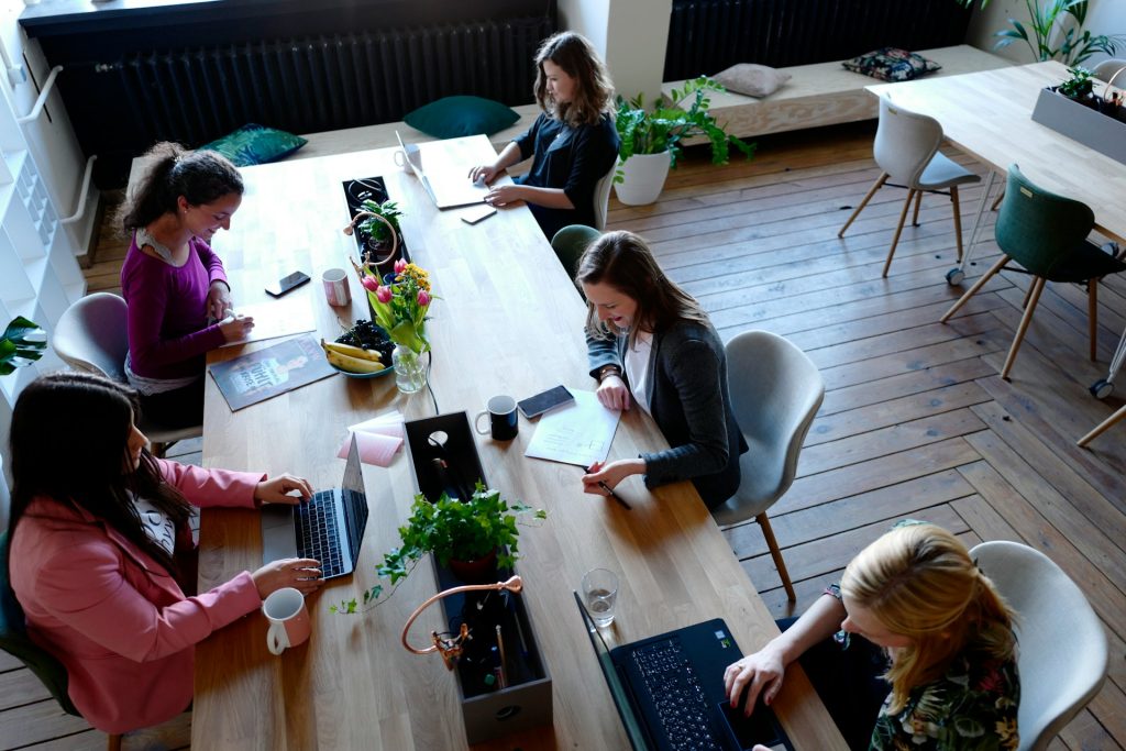Group of people sat around a table on their laptops